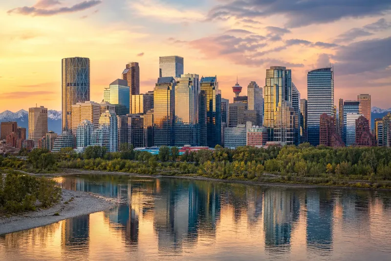 Calgary skyline beside the Bow River with the Rocky Mountains beyond